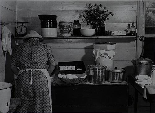 Black and white photograph of a woman making biscuits in the late 30s