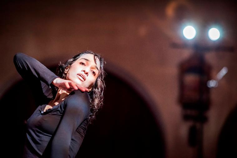 A dancer performing, with dramatic lighting in the background.