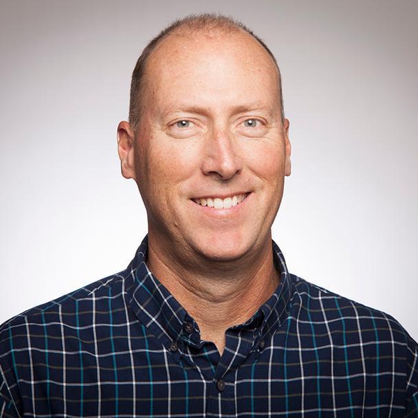 A smiling person in a checkered shirt.