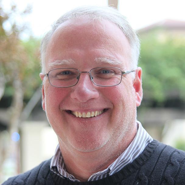 A man smiling in an outdoor setting.