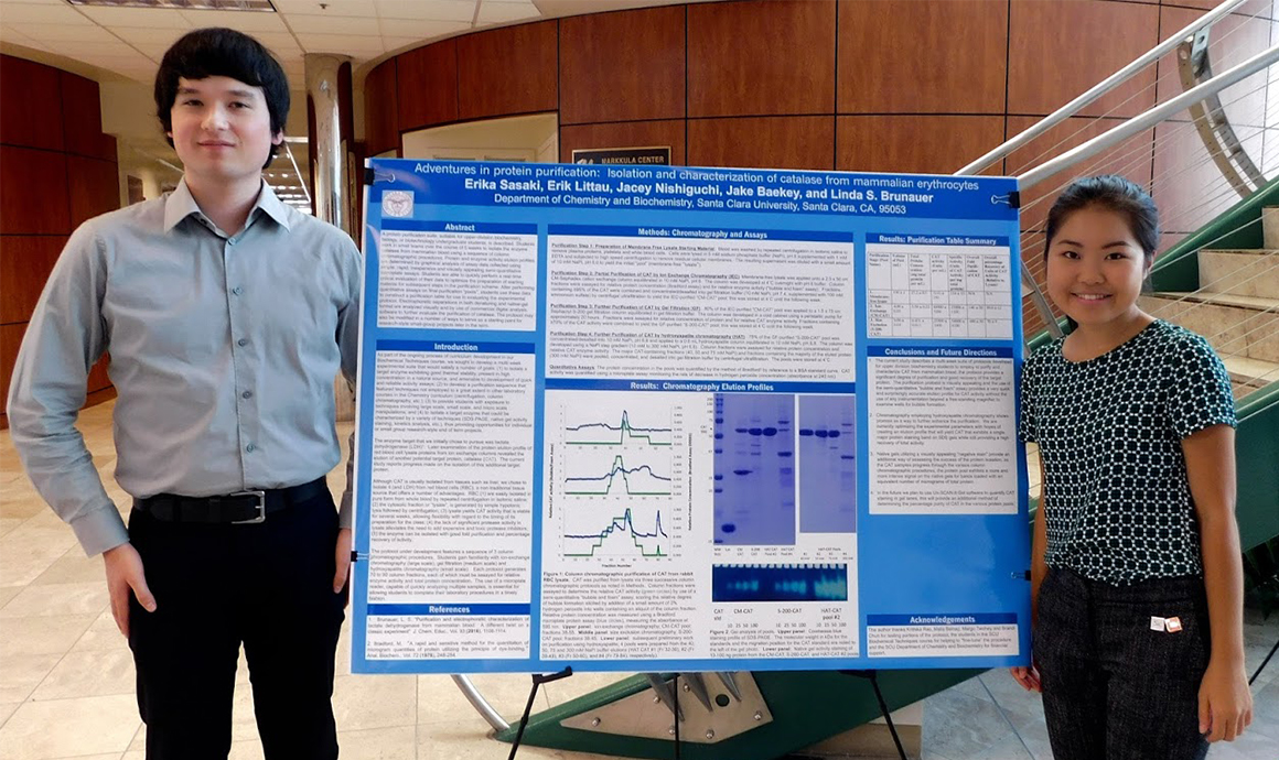 Two people posing with a scientific research poster in a lab environment.