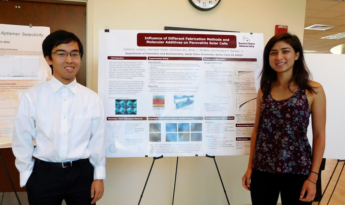 Two people standing next to a science poster titled 