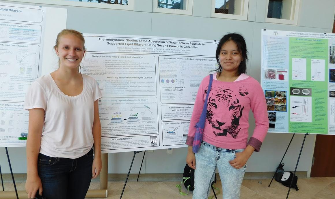 Two people standing in front of research posters in Stokes' Lab.