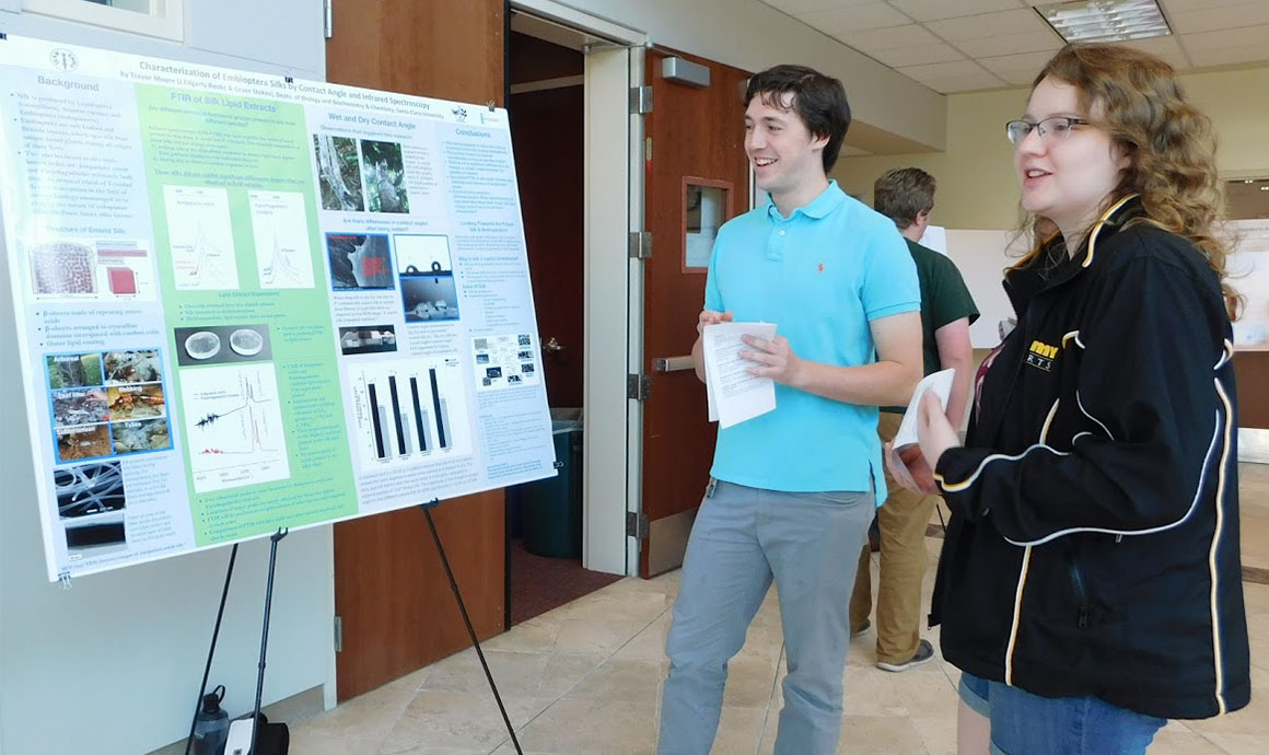 Two people discussing a poster presentation at Stokes Lab.