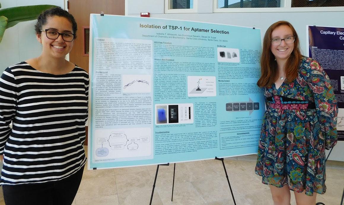 Two people standing in front of a scientific poster presentation.