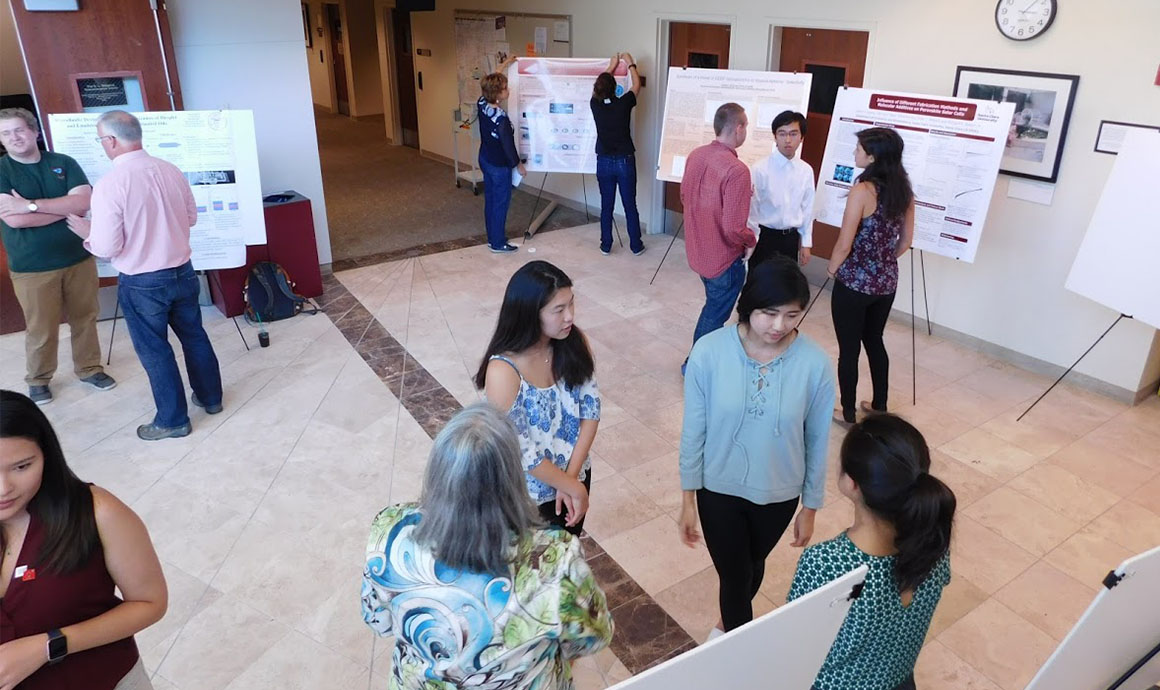 People presenting and discussing research posters in an indoor setting.