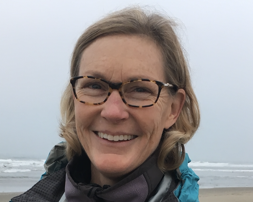 A person smiling on a foggy beach.