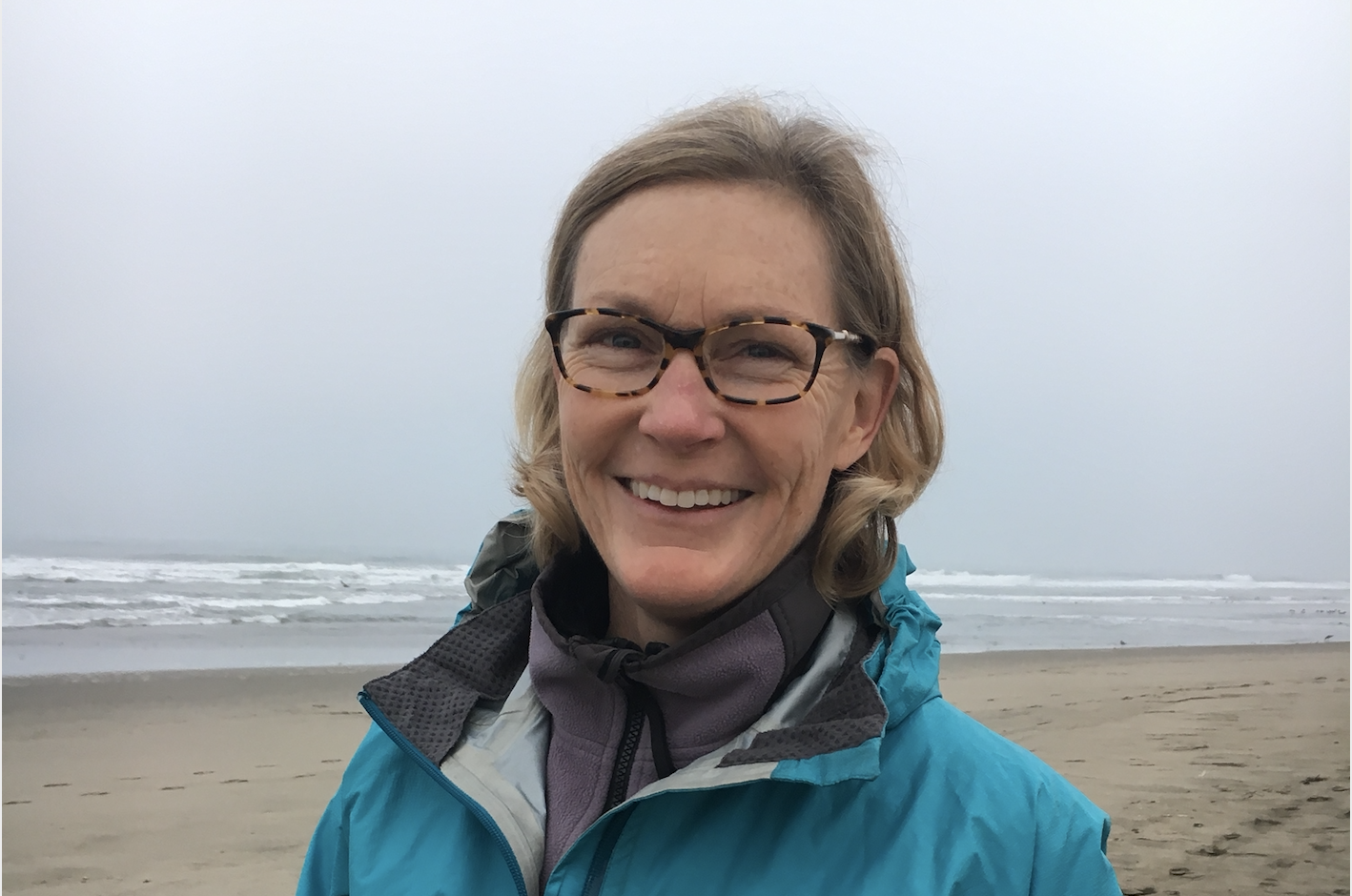 A person smiling on a foggy beach.
