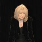 A person in black clothing against a black background.