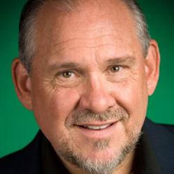 Alt text: Larry Brilliant smiling against a green background.