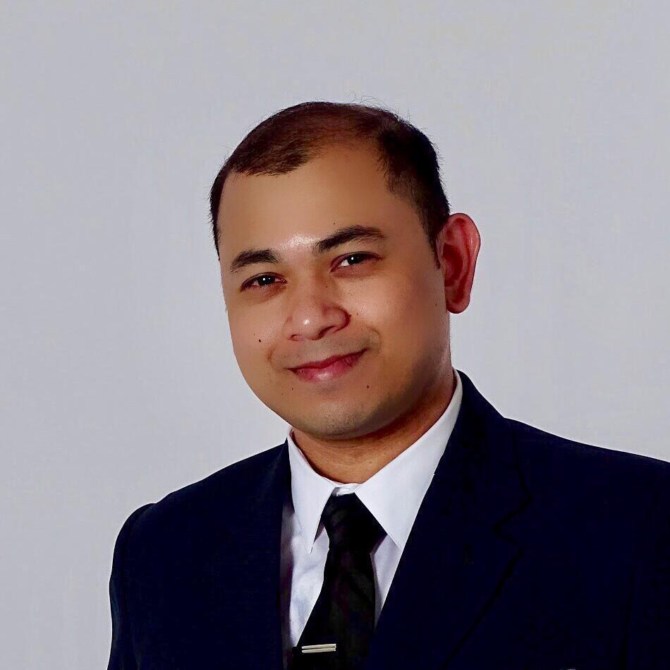 A person in a suit against a plain background.