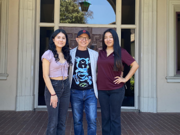 Professor Juan Velasco-Moreno with 2 female students in front of a window