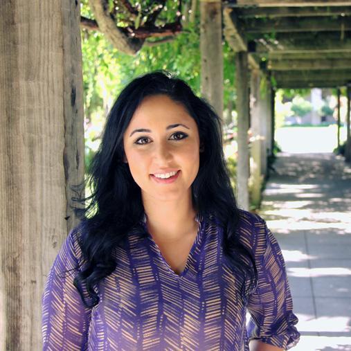 A person standing under a vine-covered pergola.