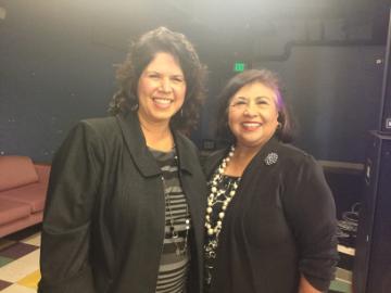 Two women smiling and posing together indoors.