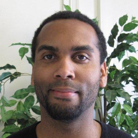 A person in front of a leafy background.