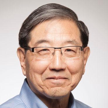 Man wearing glasses and a blue shirt against a light gray background.