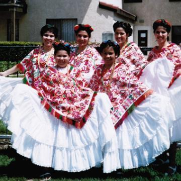 A group of people in colorful, traditional folklórico dresses. 