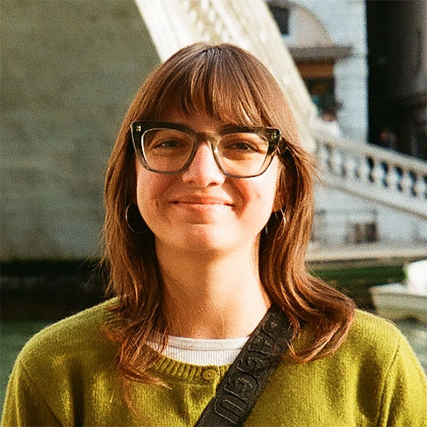 Clara Helm outside near a river, bridge and buildings in the background