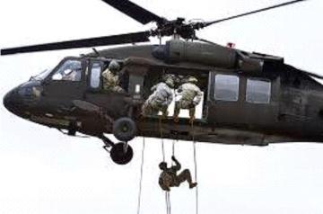 Soldiers rappelling from a helicopter during an air assault operation.