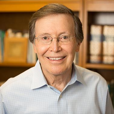 A person smiling in front of bookshelves.