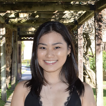 A person smiling in an outdoor setting with a pergola.