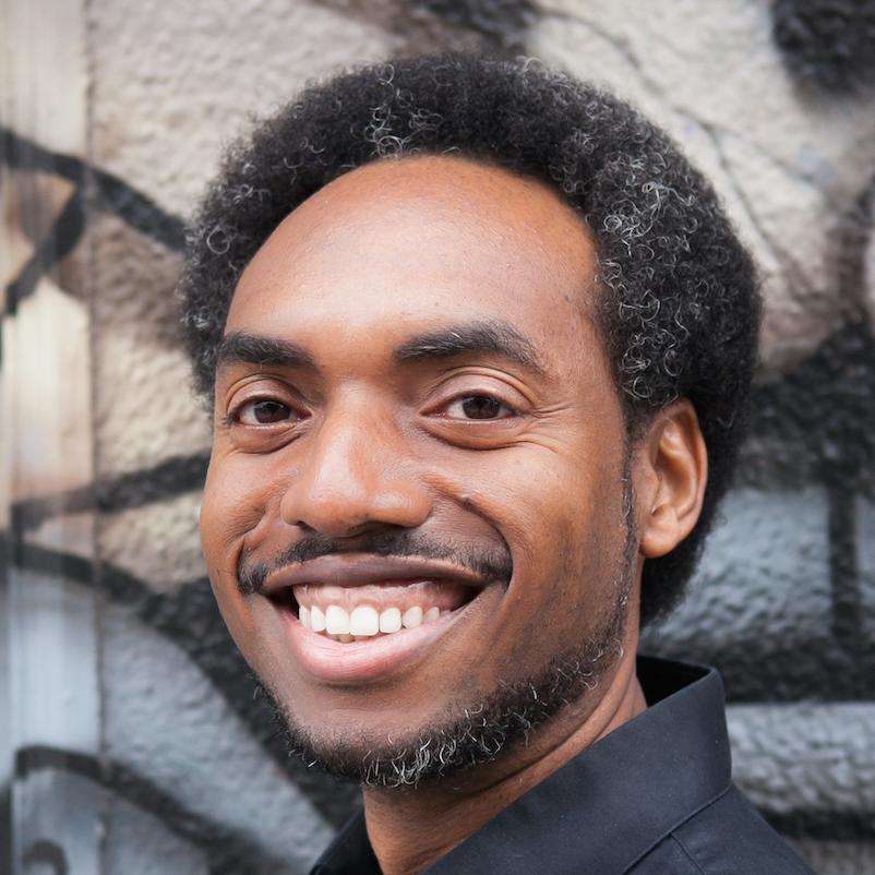 A smiling person in front of graffiti art.