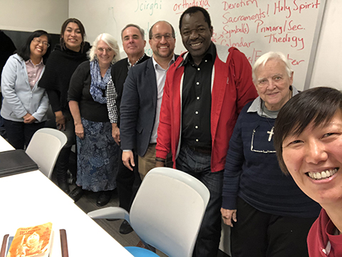 students and professor standing in front of white board