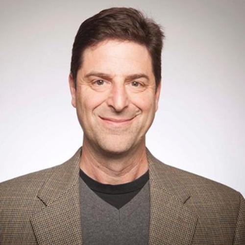 A man wearing a blazer, smiling at the camera.