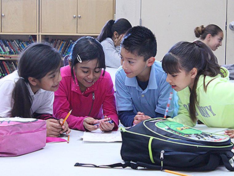 Four children sitting at a table, engaged in arts and crafts activities.