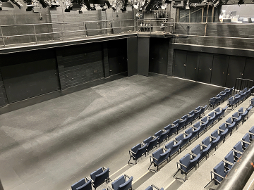 Looking down from the catwalk to a black box theatre with blue seats