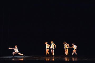 Line of dancers walking across the stage into the light