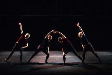 4 dancers posed with an arm bent over their heads