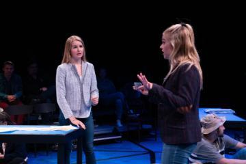 Two people talking on stage during a theatre performance.