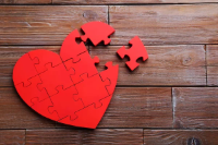 Incomplete red heart of puzzle pieces on a wooden background