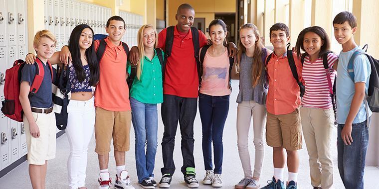 Students with arms around each others shoulders in school hallway 