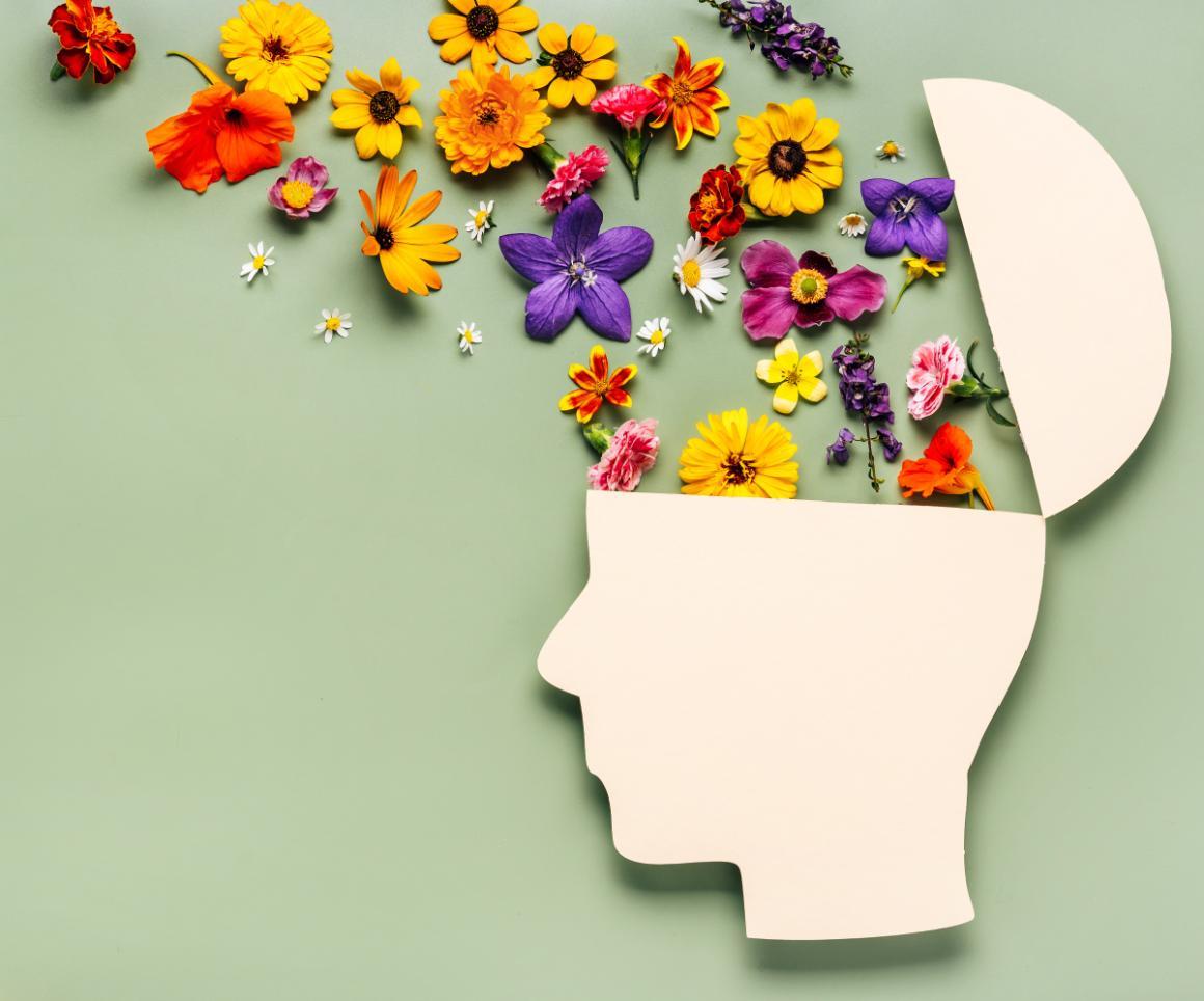 Paper human head symbol and flowers on green background