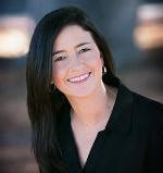 A smiling woman wearing a black top with a blurred background.