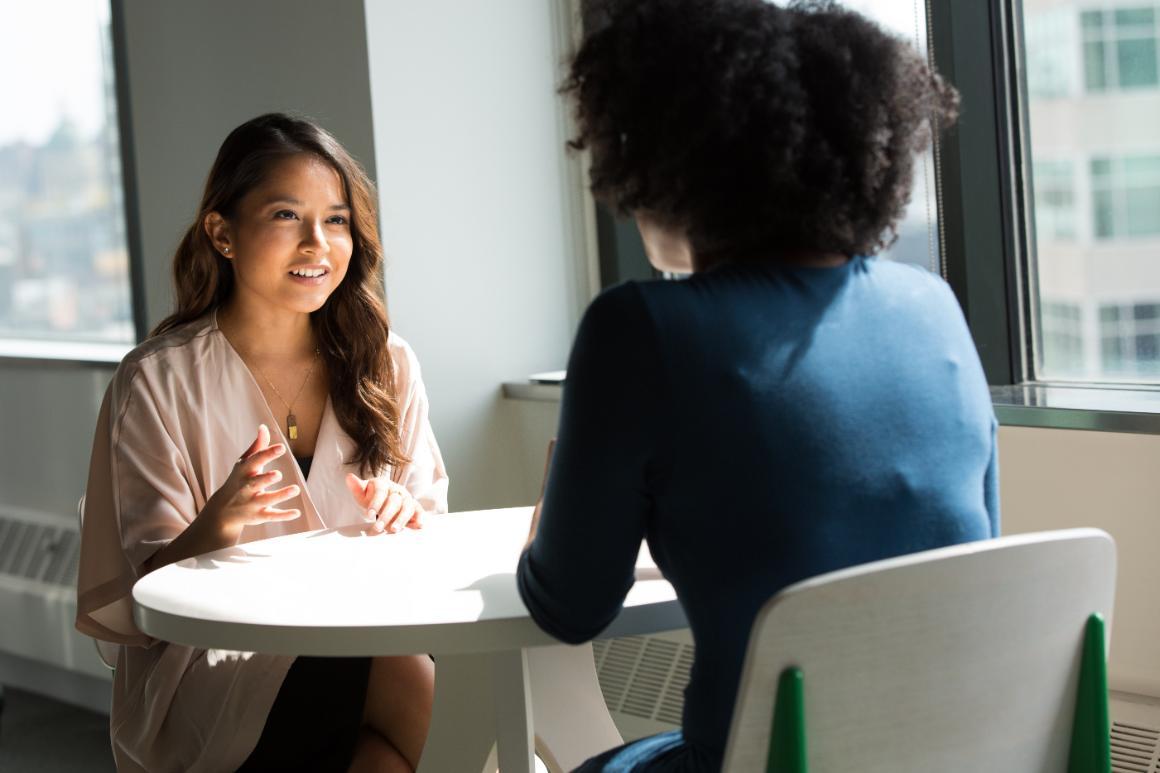 Two people seated at a table having a discussion in an office.