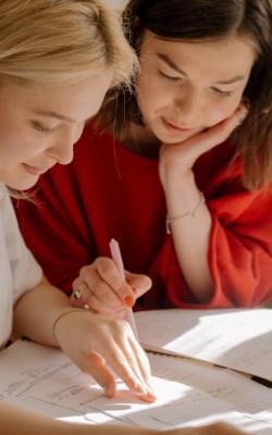 Two people studying together, one pointing to a book.