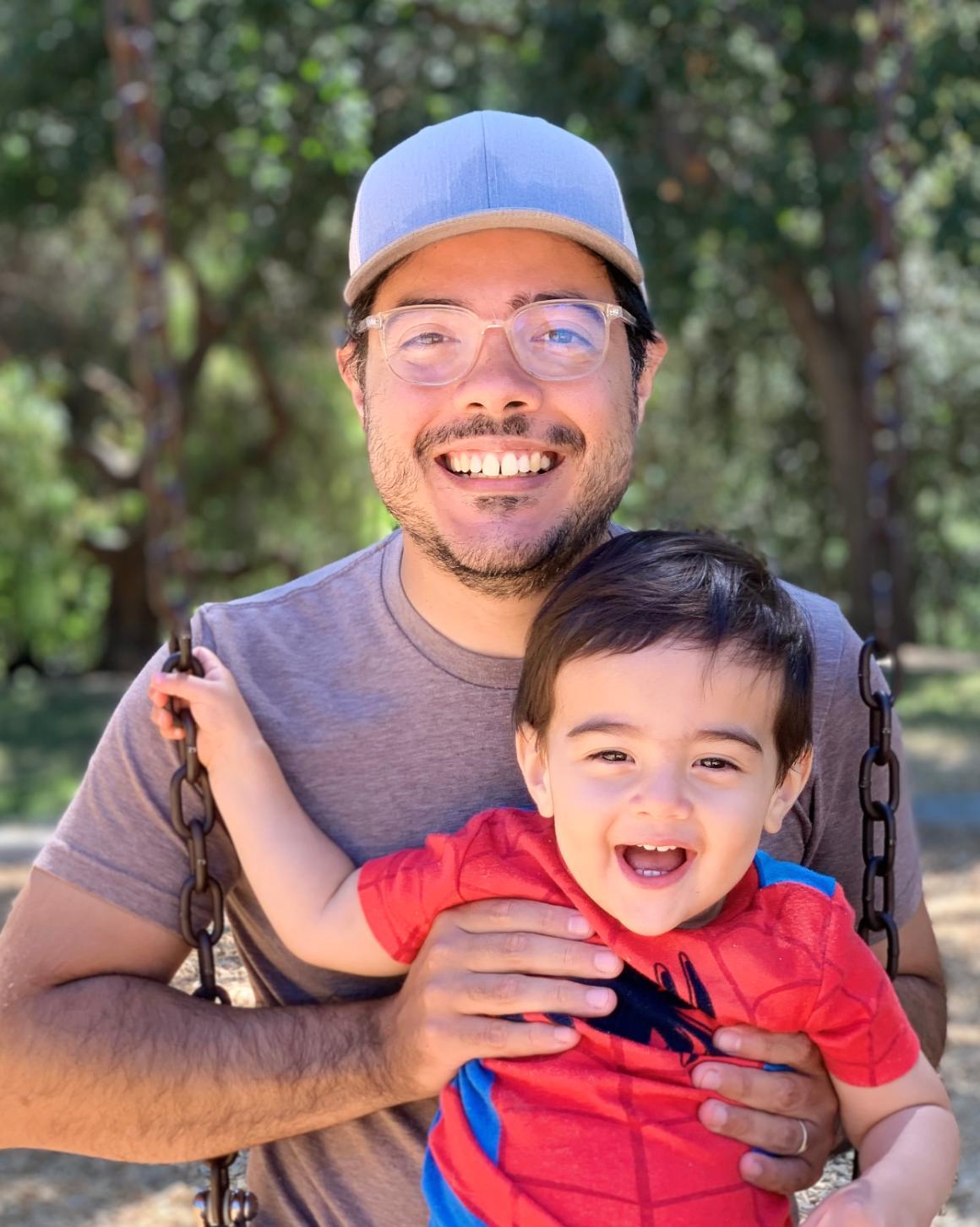A man holding a smiling child outdoors.