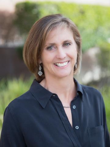 A woman wearing a black shirt, smiling outdoors.