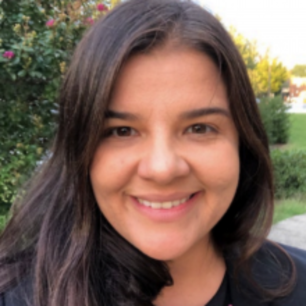 Dr. Sophia Rodriguez smiling outdoors with greenery in the background.