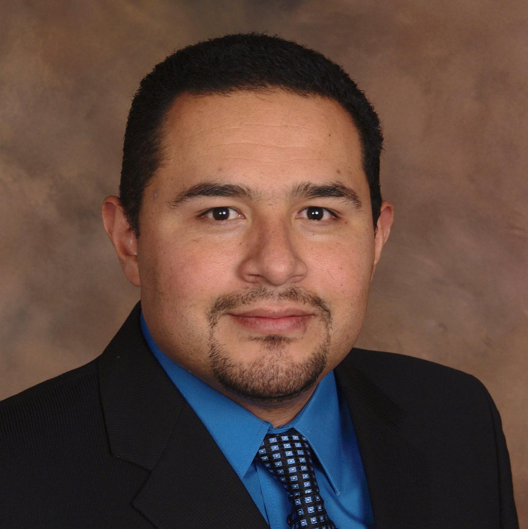 A man in a suit with a blue shirt and tie.