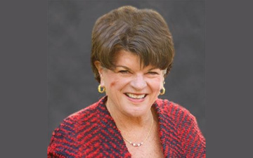 A woman in a red checkered blazer smiling.