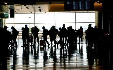 Silhouettes of people in an airport terminal with luggage.