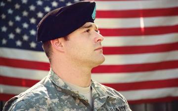 Soldier standing in front of a flag