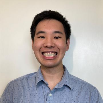 A man smiling in a collared shirt against a plain background.