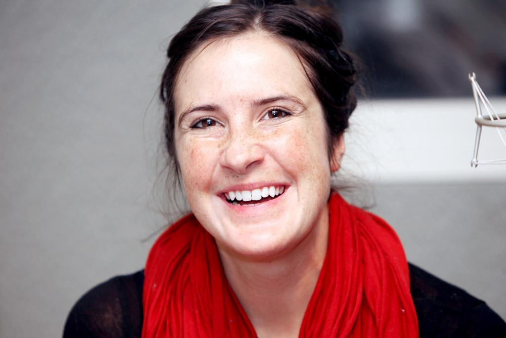 A person smiling, wearing a red scarf. image link to story