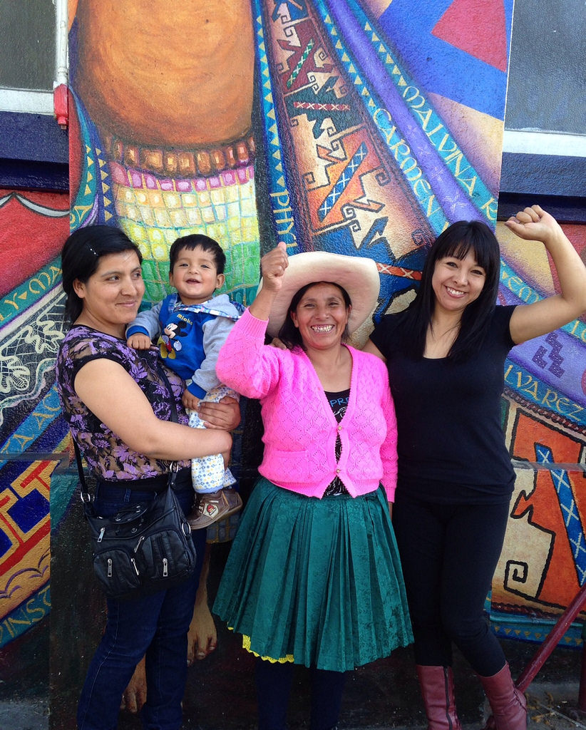Three women and a child in front of a colorful mural. image link to story