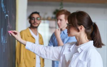 Three students working on a blackboard. Photo credit: fauxels/Pexels 